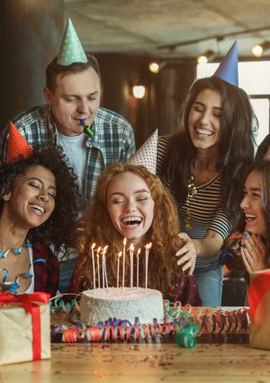 Happy friends congratulating girl on surprise birthday party, copy space